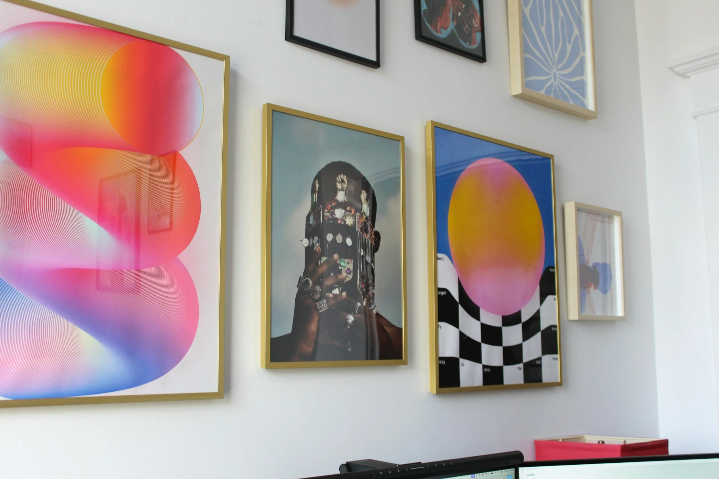 Gallery wall with framed abstract art, portraits, and geometric designs in a modern interior.