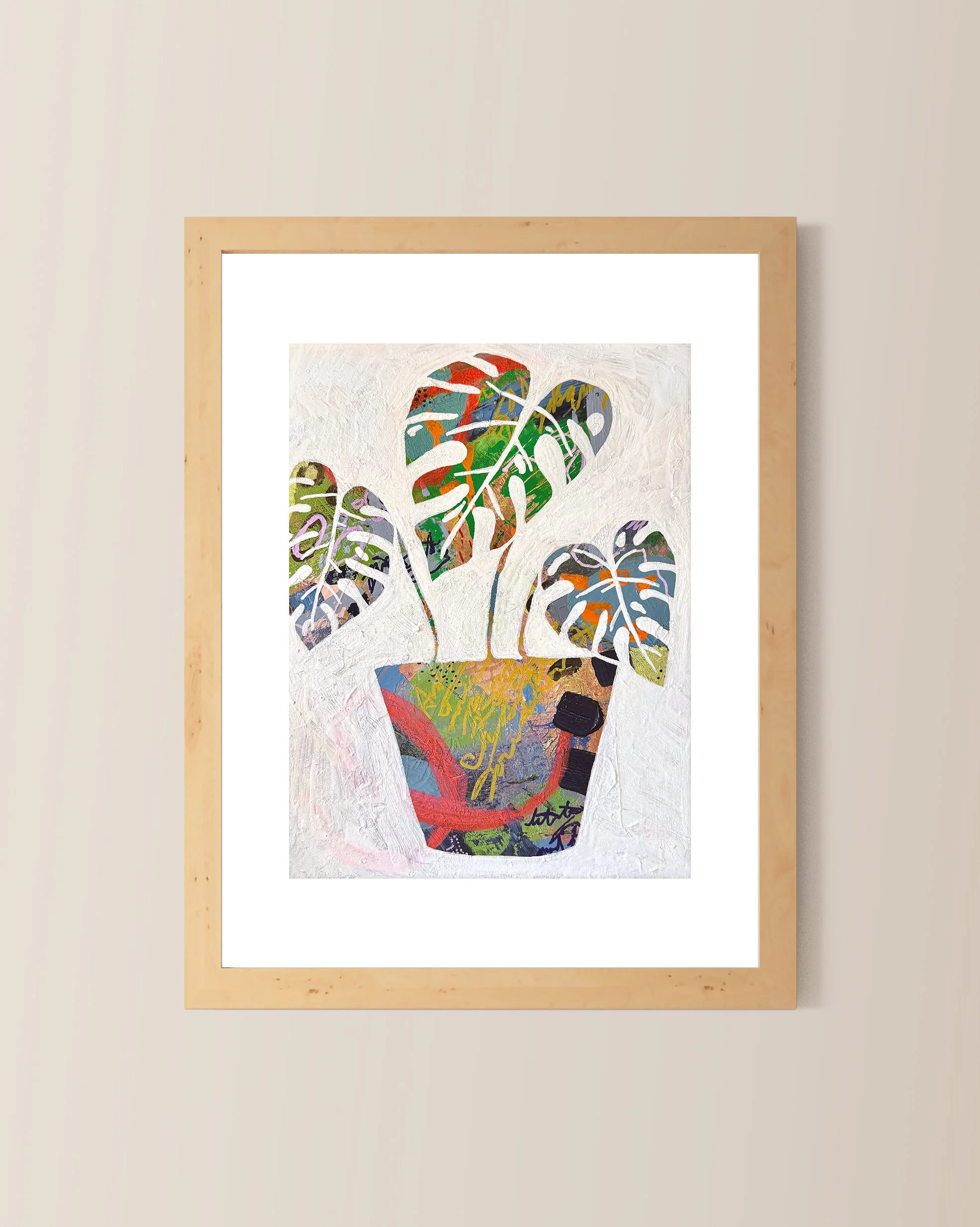 A matted print of a colorful abstract painting of a potted monstera plant with large, patterned leaves framed in a light wooden frame.