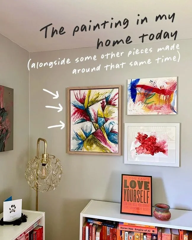 Home wall display annotated 'The painting in my home today (alongside some other pieces made around that same time)' showing three framed abstract paintings in primary colors, hung above a bookshelf filled with books and decor.