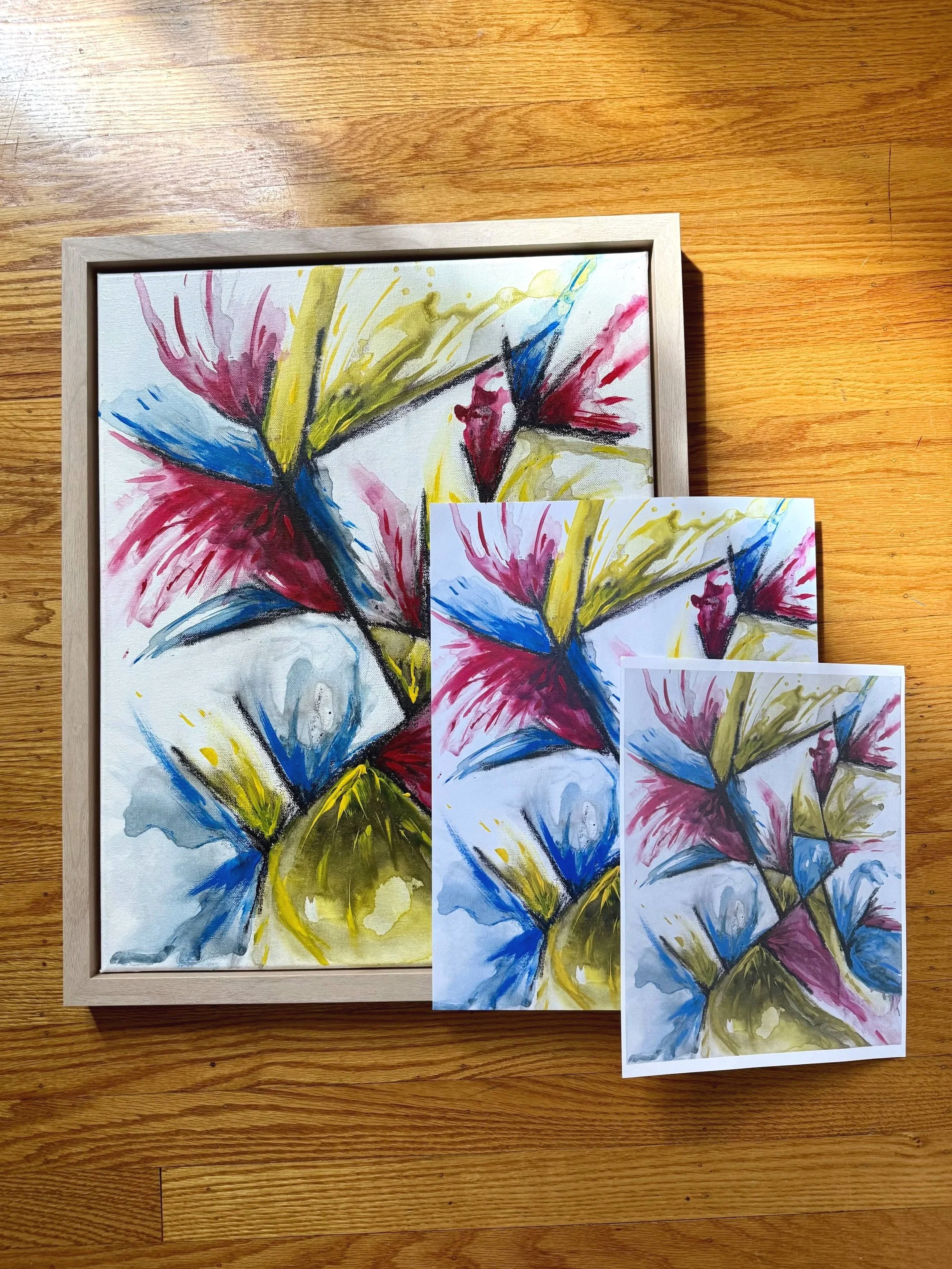 Here the original red, yellow, and blue painting is shown in a light wood frame. On top of its bottom right corner is the 11x14 giclée, which is in turn topped by the 8x10 copy paper printout.