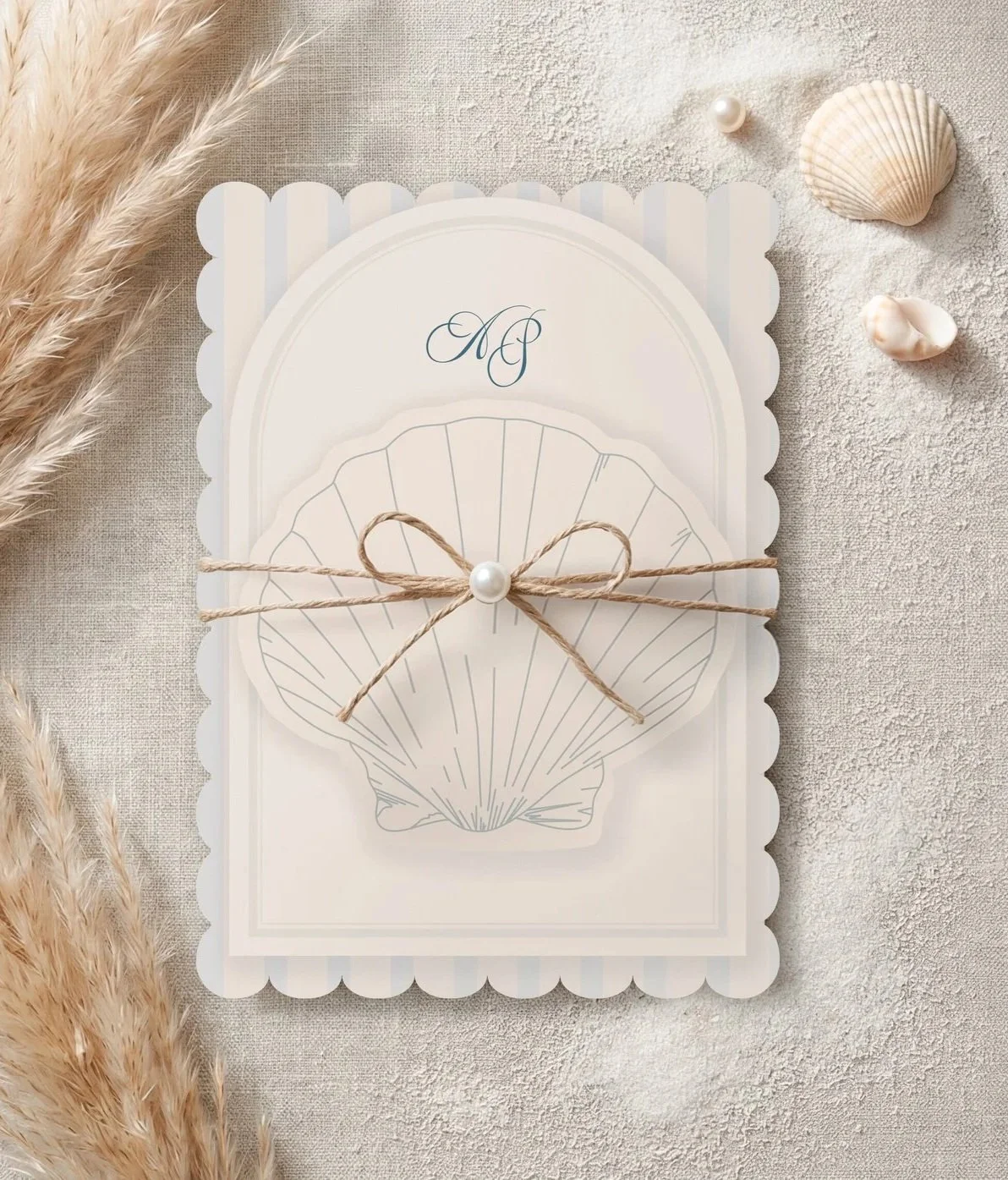 A white scalloped wedding invitation with a seashell illustration, tied with a string bow with a pearl at the knot.
