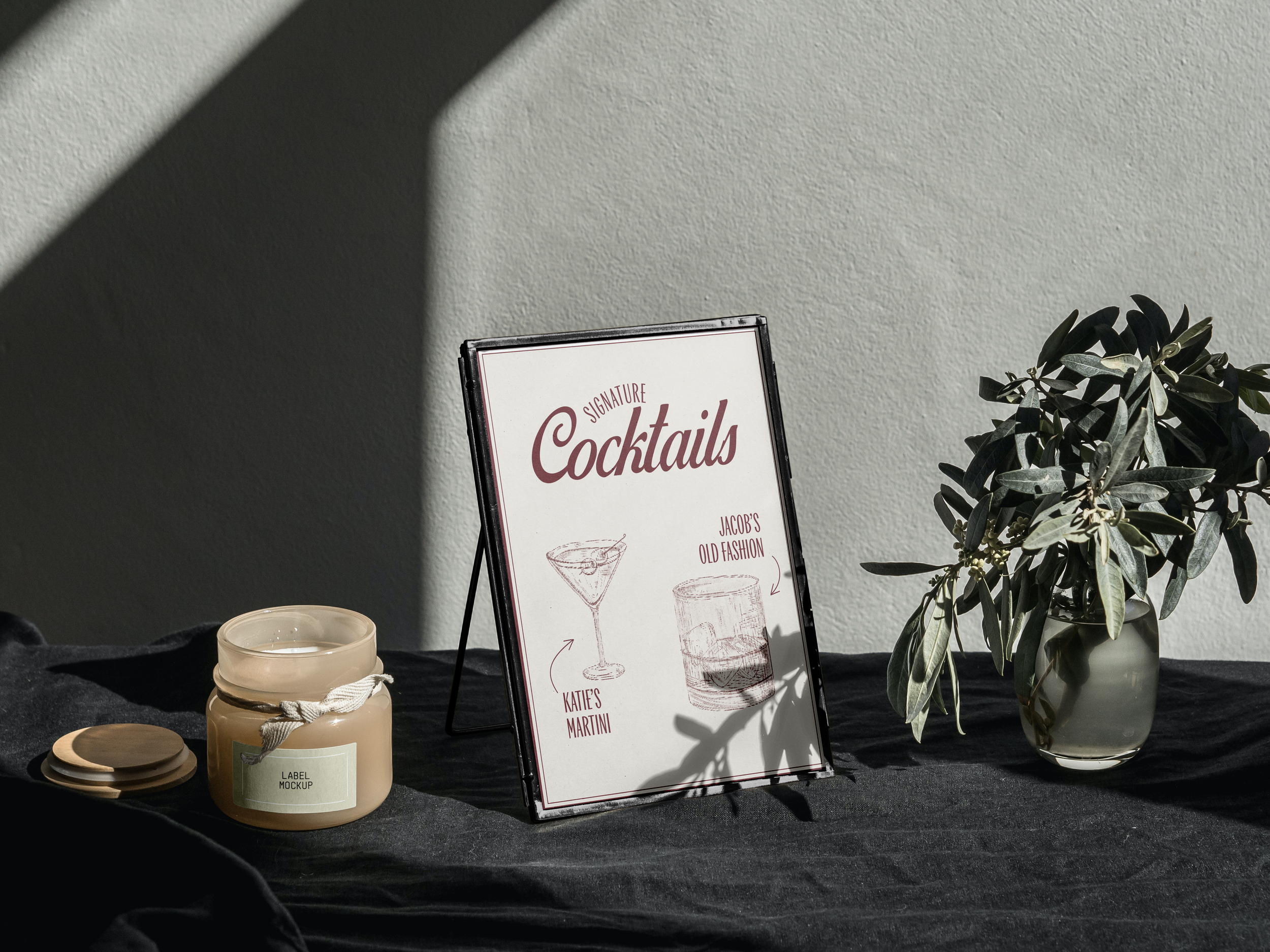 A framed sign listing signature cocktails with illustrations and labels.