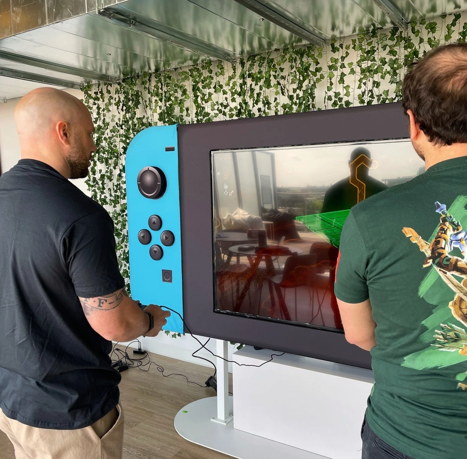 Deux hommes jouent à une console de jeu Switch géante lors d'un lancement de presse
