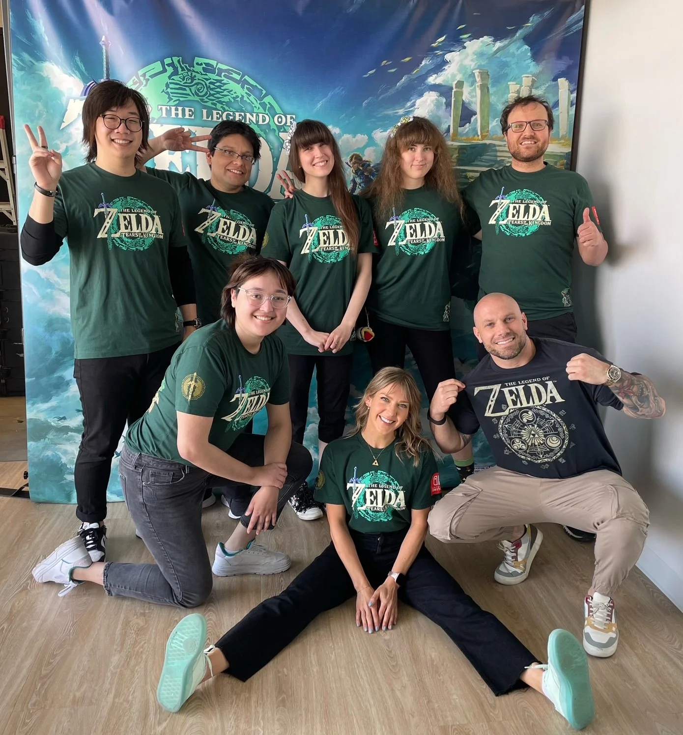 Groupe de personnes posant pour une photo, portant des t-shirts promotionnels du jeu vidéo "The Legend of Zelda".