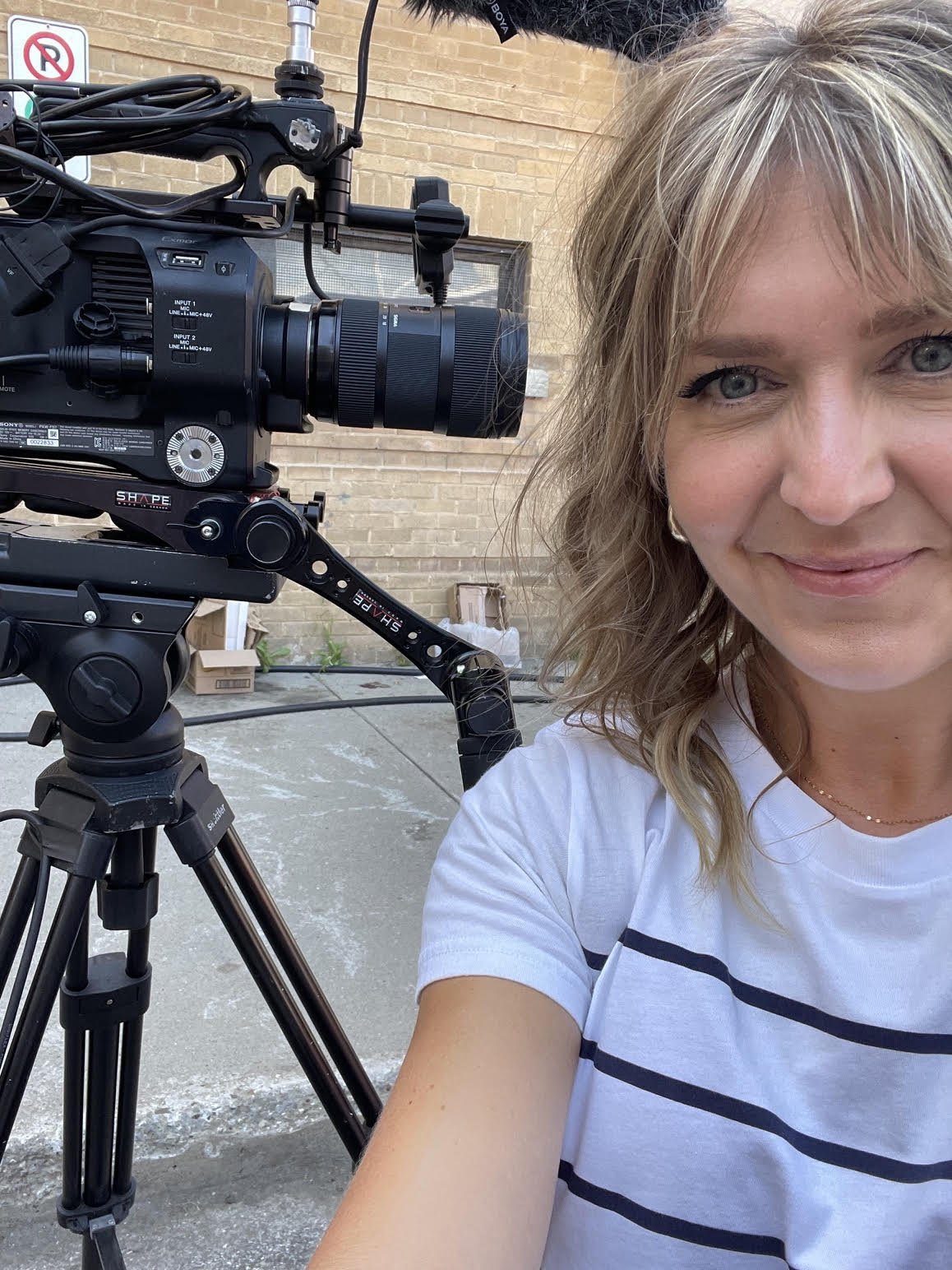 Julie, femme souriante posant pour un selfie devant une caméra de tournage