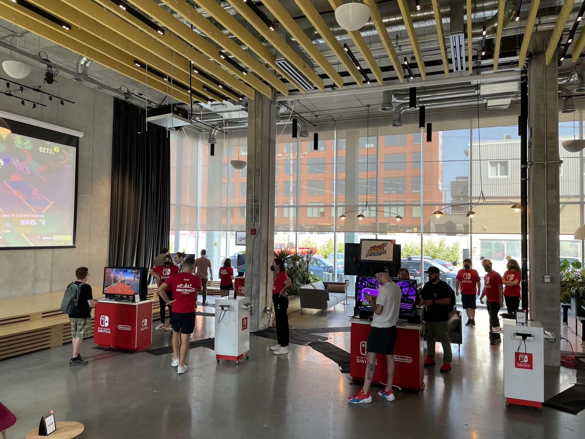 Mini foire pour Nintendo avec des stands et des groupes de jeunes et d'adultes en activité.