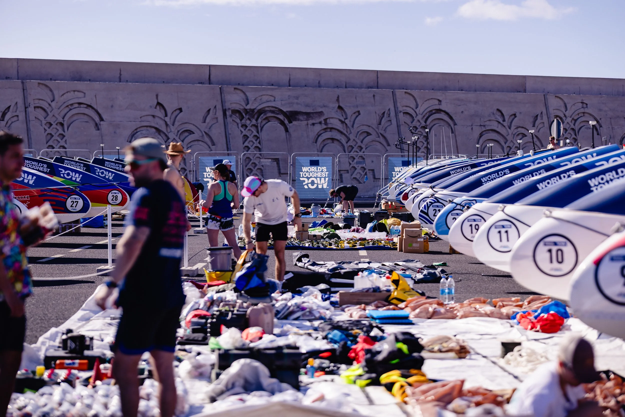 Scene from a rowing event with equipment, boats, and participants preparing or cleaning up.