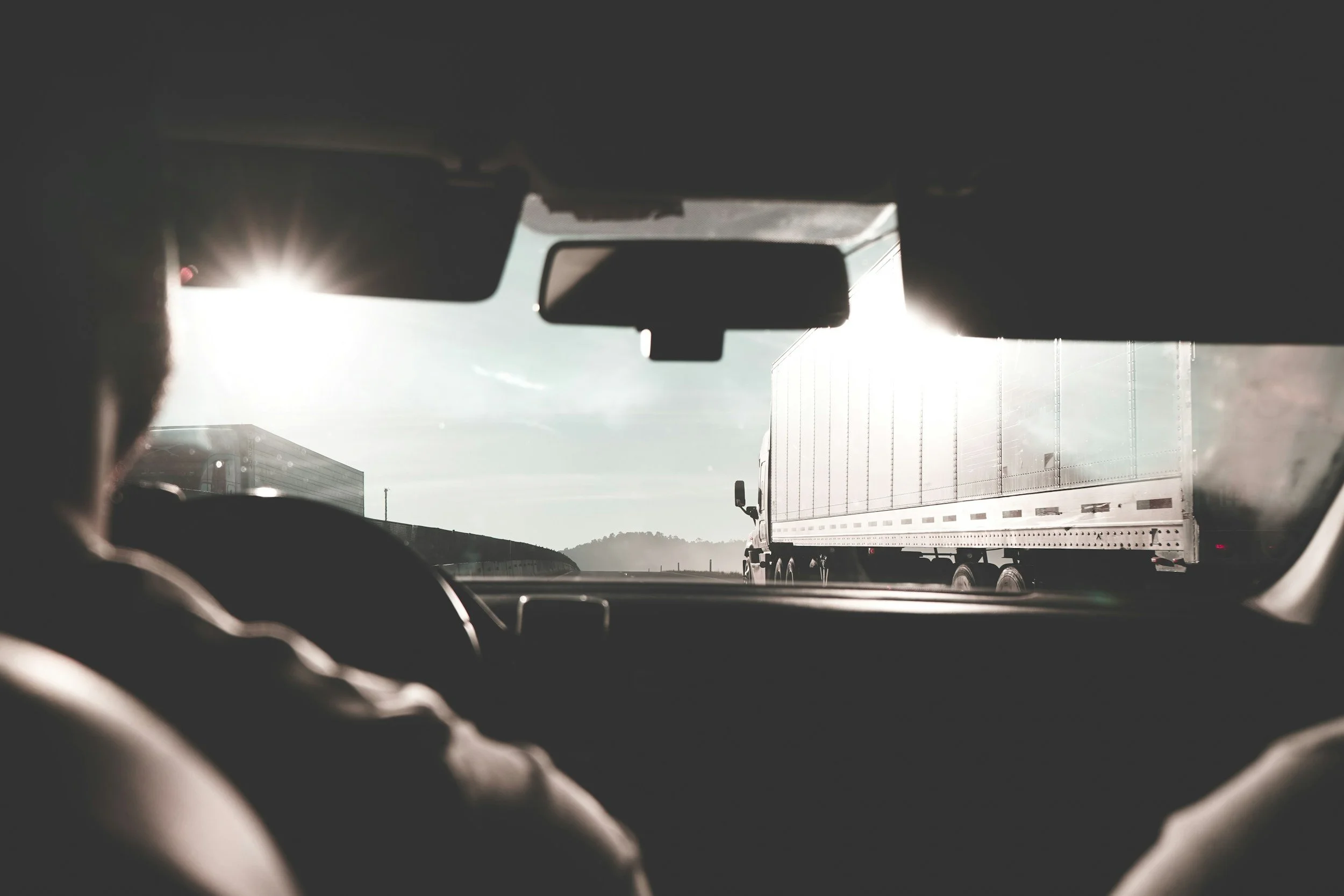 Car driver following behind a semi-truck on a highway, observing traffic ahead.