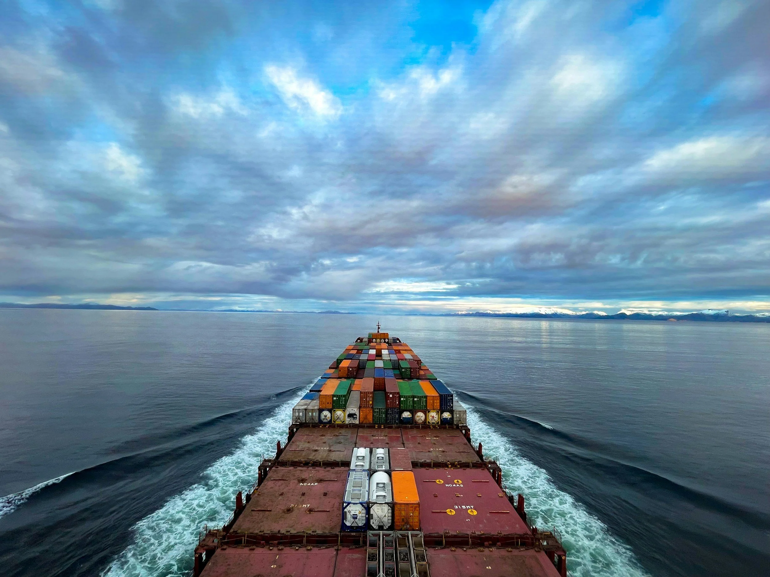 Cargo ship traveling across the open ocean under a clear and beautiful sky, representing ocean freight transportation and global shipping routes.