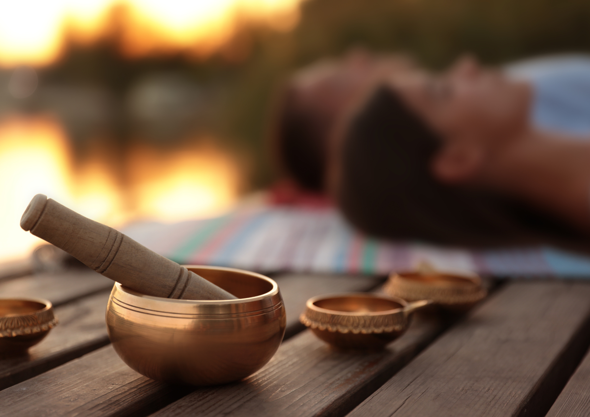 Bild på en tamburinställning med flera insatser i kopparskålar, en person i bakgrunden ligger ned på en matta i en yogastudio med solsken utanför fönstret.