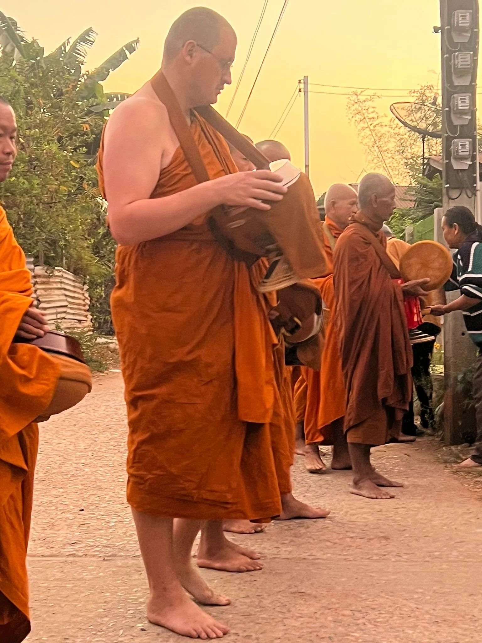Buddhist monks standing in a row with their feet flat on the ground, barefoot, during sunset or sunrise.
