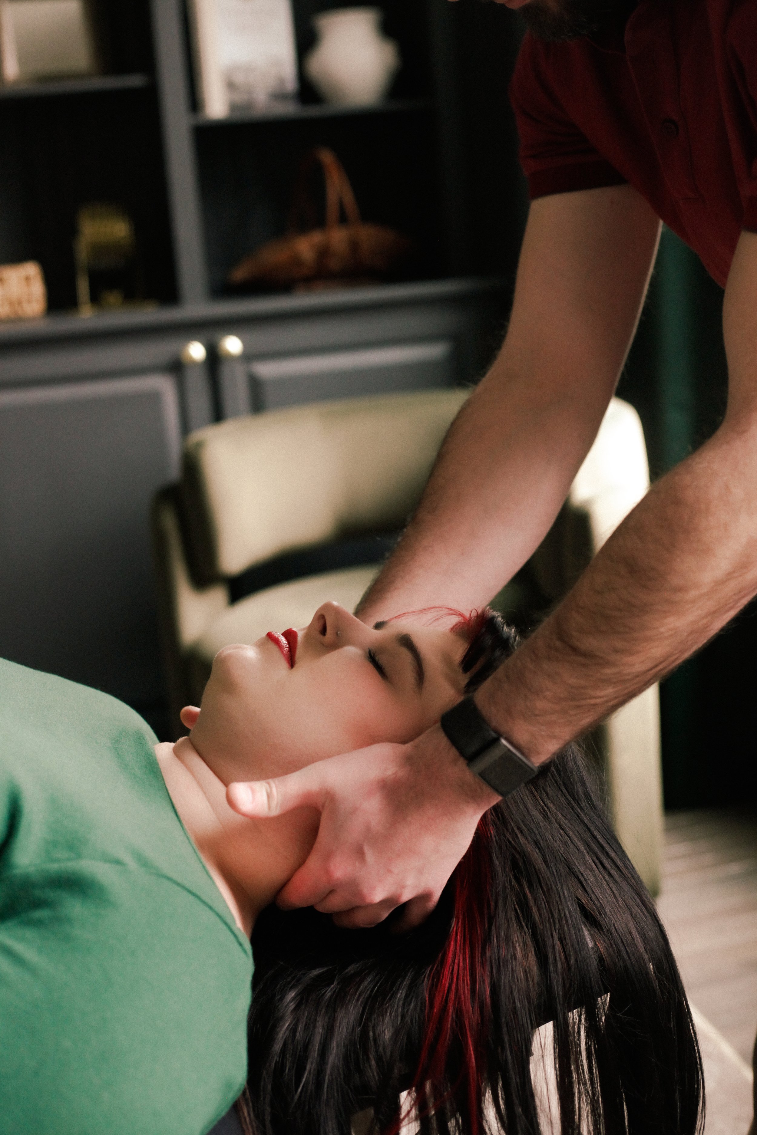 Woman lying on a table with eyes closed receiving chiropractic care from Dr. Evan.
