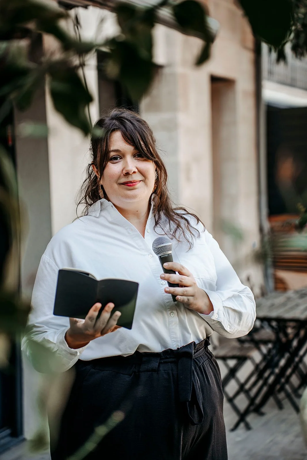 Aurore Sciacca, célébrante et accompagnante du deuil,  avec un micro et un cahier, parlant lors d'une cérémonie en plein air.