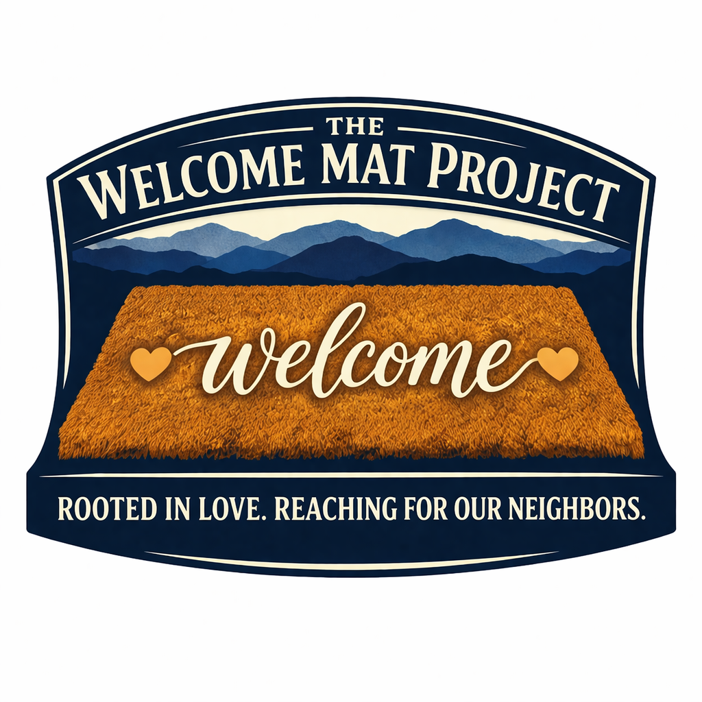 Logo for The Welcome Mat Project with a mountain landscape background and a welcome mat in the foreground, featuring the words 'welcome' with hearts on either side. The tagline reads 'Rooted in love. Reaching for our neighbors.'