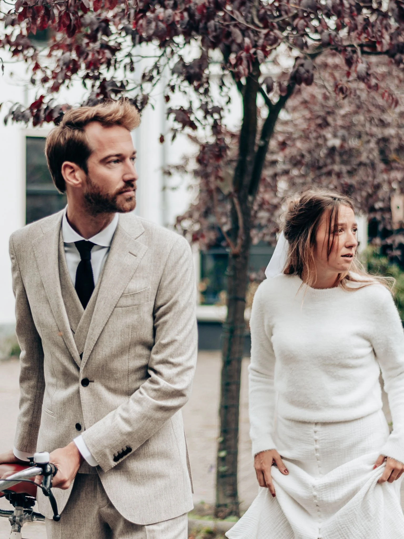 Een bruid en een bruidegom staan buiten, de bruid lijkt verdrietig.