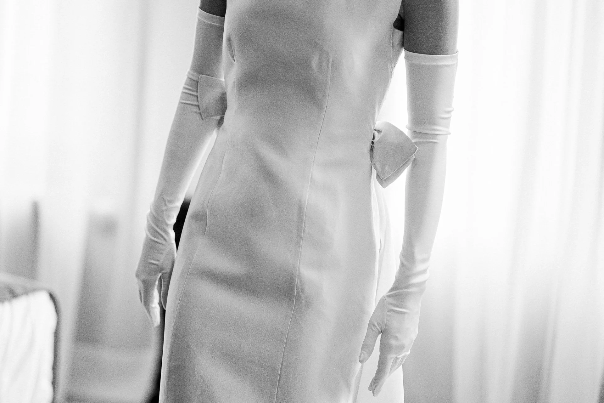 Een persoon draagt een witte verpleegstersbroek en handschoenen, gezien van de achterkant. Alles is in zwart-wit.