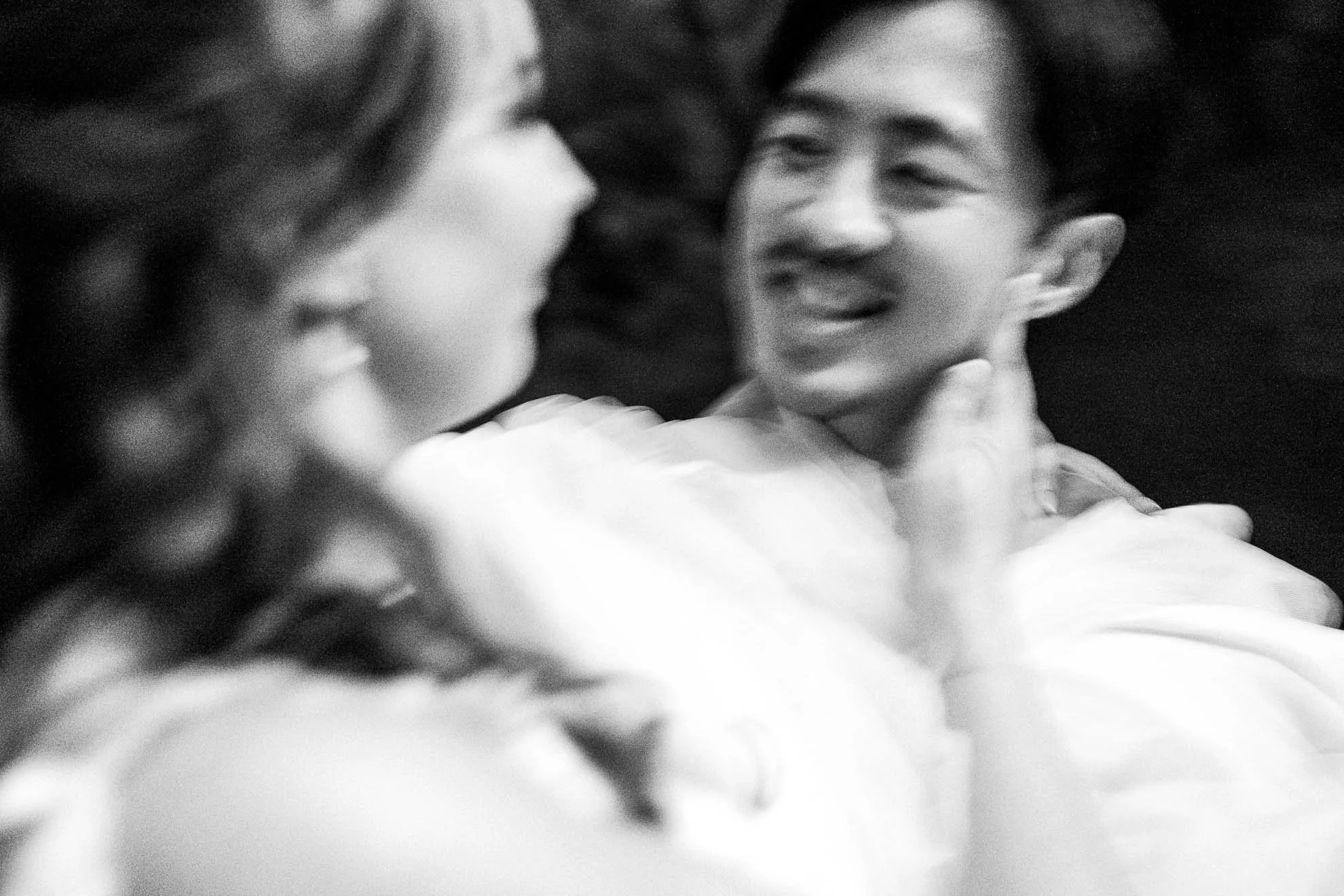 A black-and-white photograph of two people sharing an intimate moment, with one person's face close to the other's and a gentle, happy expression.