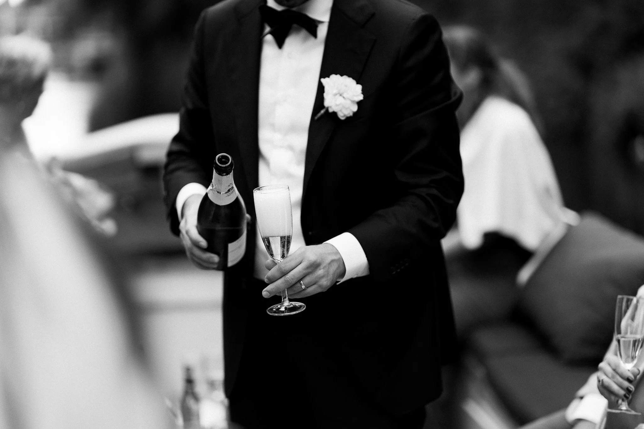 Een man in een zwart pak schenkt champagne tijdens een feestelijke gelegenheid, mogelijk een bruiloft.