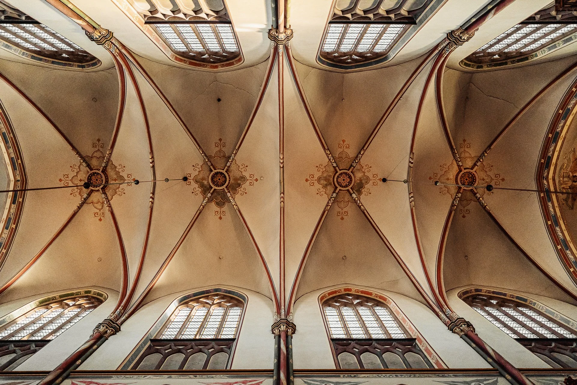 Interieur van een gotische kerk, met gekleurde gewelven en hoge ramen.