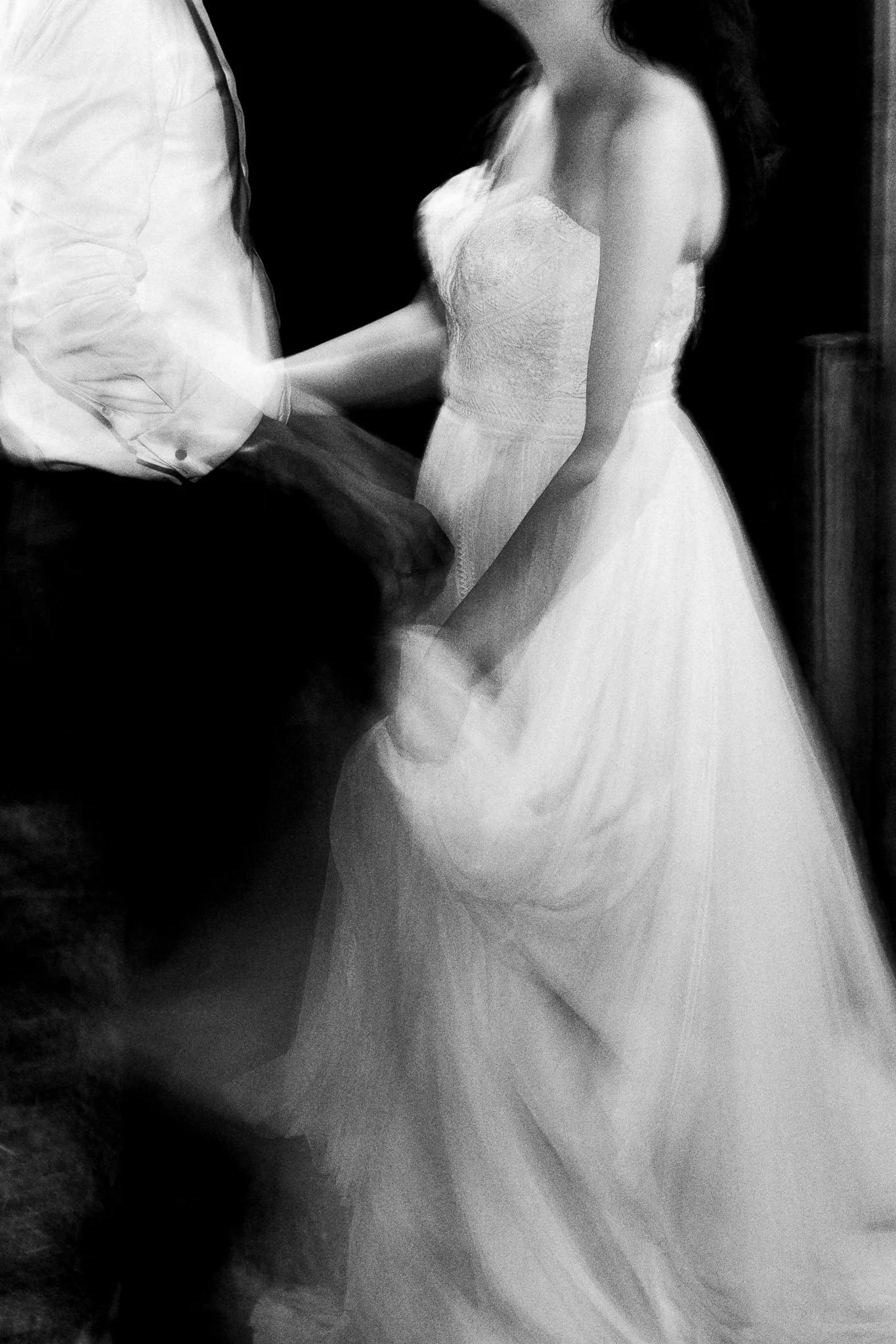 Een vrouw in een witte trouwjurk, getekend door beweging, houdt handen vast met een man.