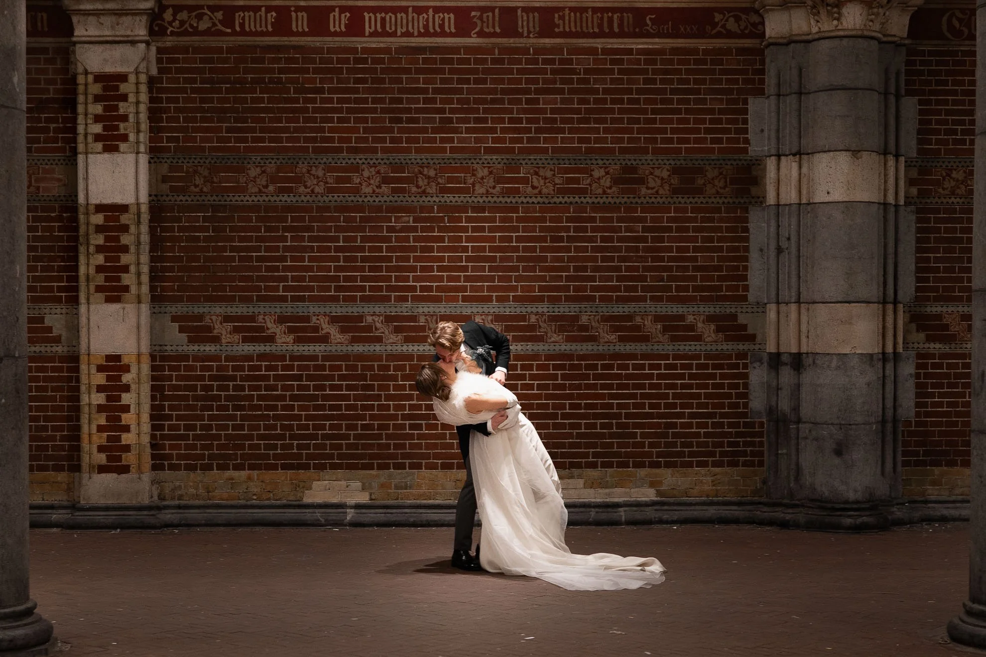 A couple sharing a dance in front of a brick wall during a wedding.