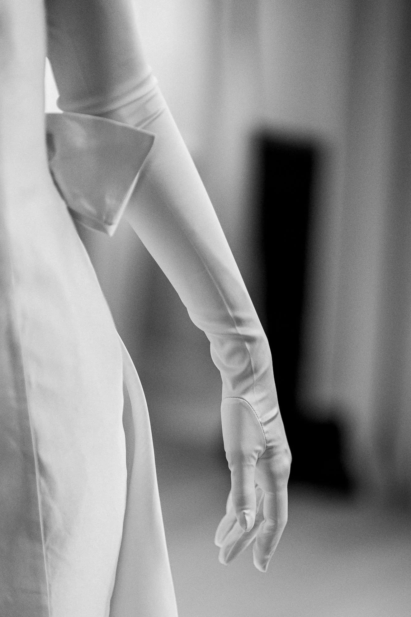 Close-up of a hand wearing a white glove, holding a face mask, with a blurred background.