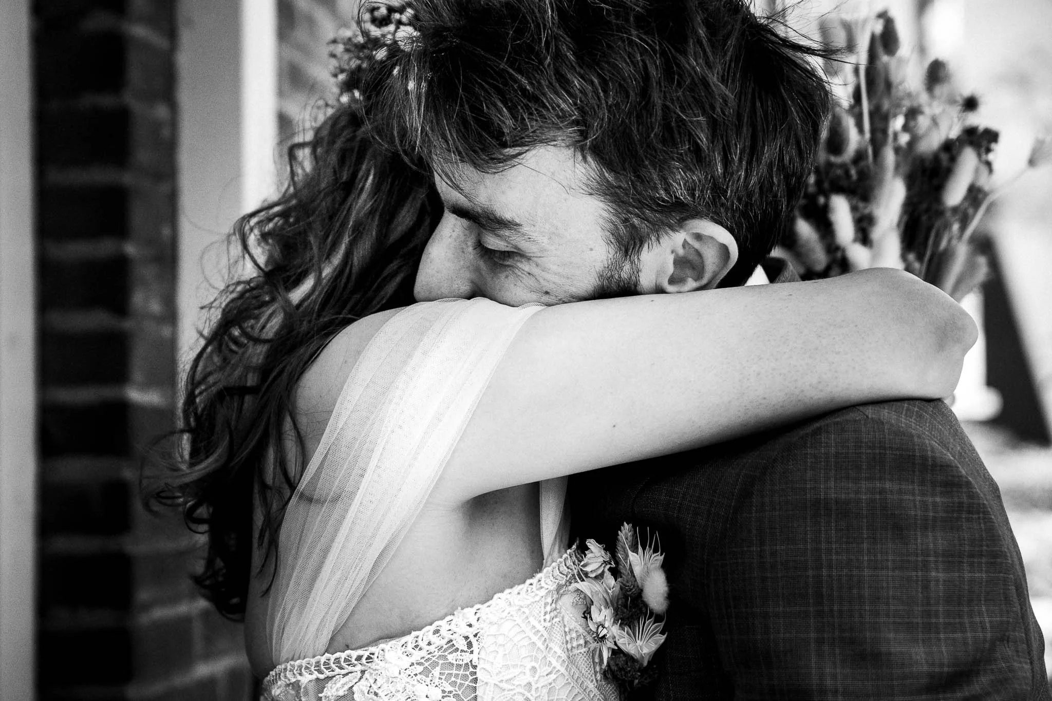 Twee mensen omarmen elkaar innig, een man en een vrouw, mogelijk op een huwelijksfeest, in zwart en wit