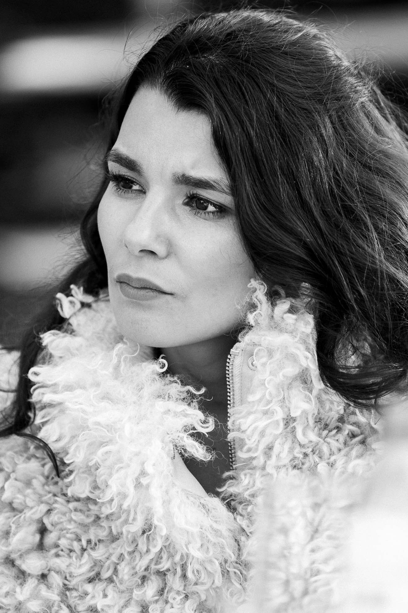 Black and white photo of a woman with long dark hair wearing a textured, fluffy jacket and a zippered top.