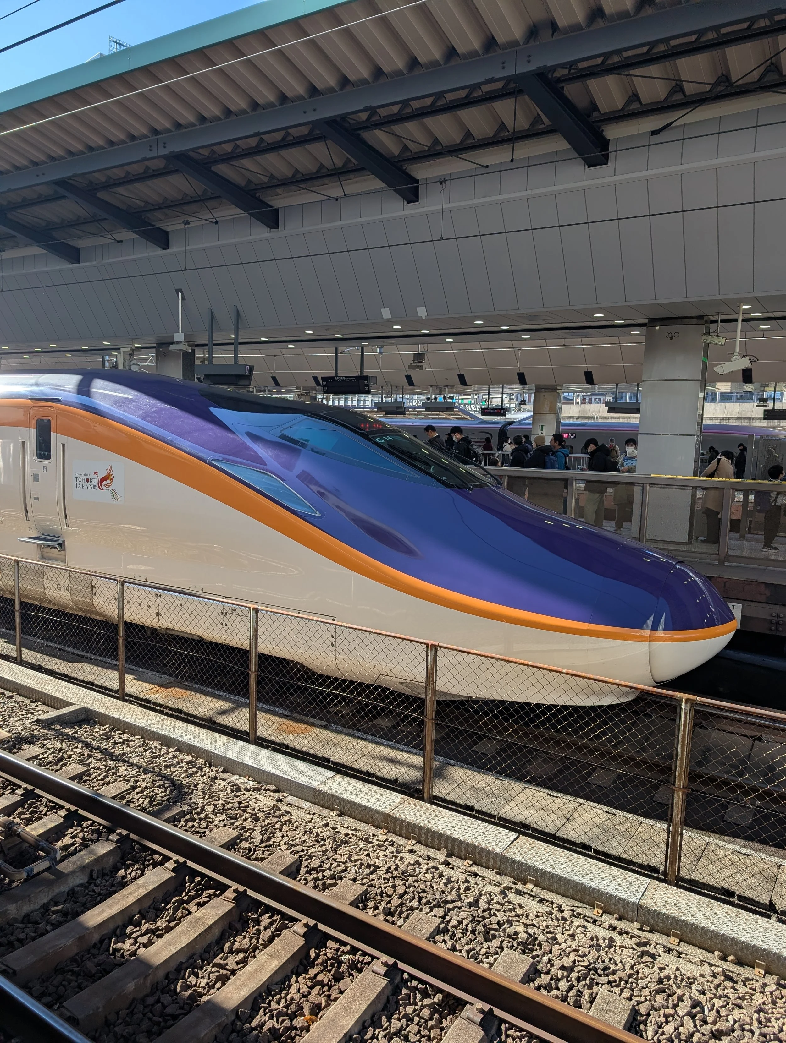 A sleek, modern bullet train at a train station with passengers boarding on the platform.