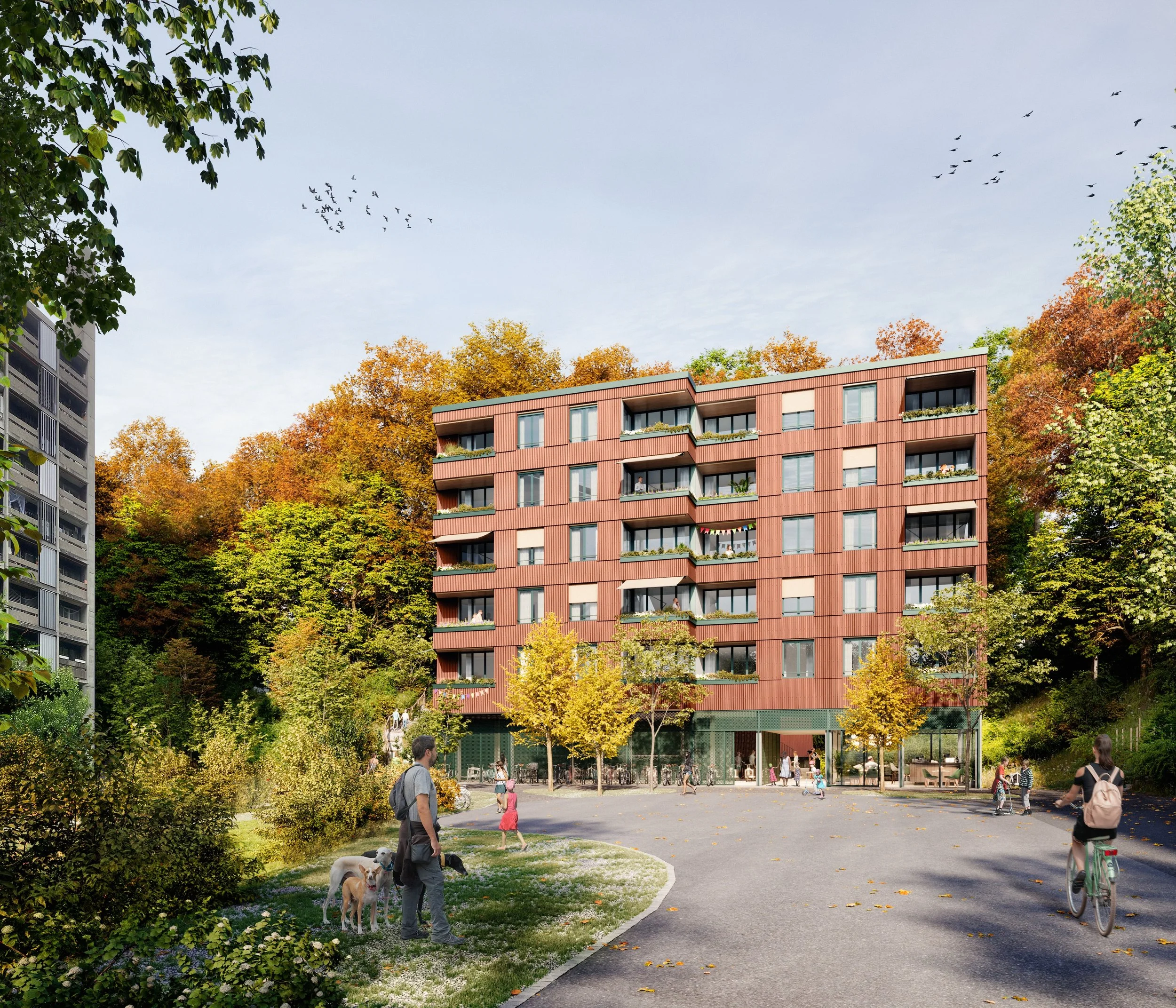 Ein moderner, roter Ferienwohnbau mit mehreren Balkonen, umgeben von buntem Herbstlaub, in einem Park mit Menschen, Hunde und Fahrradständern im Vordergrund, unter blauen Himmel mit fliegenden Vögeln.