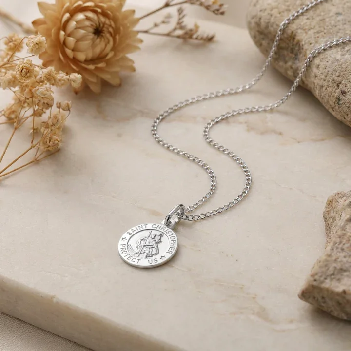 Sterling Silver St Christopher pendant, shown on marble pad with sea stones and dried botanicals
