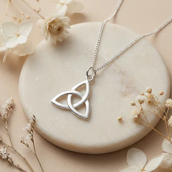 Sterling Silver Celtic Trinity Knot Pendant, open triquetra design, high mirror polish, shown on sea stone with dried botanicals