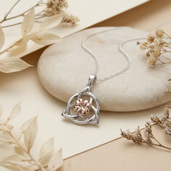 Sterling Silver & Rose Gold Celtic Trinity Knot Pendant, rose gold clover centre, shown on sea stone with dried botanicals