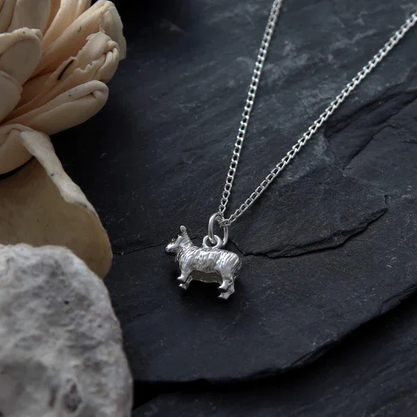 Sterling Silver Scottish Sheep Pendant, sculpted three-dimensional form, engraved fleece detail, shown on Scottish slate with sea stone and dried botanicals