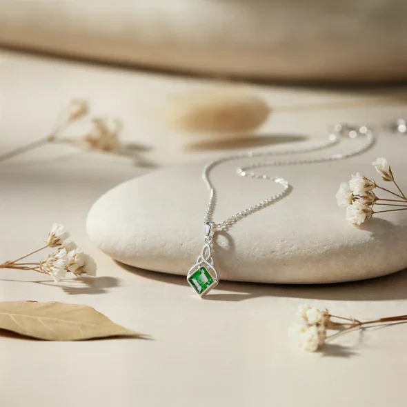 Sterling Silver Celtic Knotwork Pendant, square-cut green CZ stone, bezel set, shown on sea stone with dried botanicals