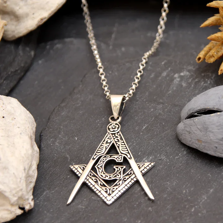 Sterling Silver Masonic pendant, square and compass with G, shown on Scottish slate with sea stones and dried botanicals