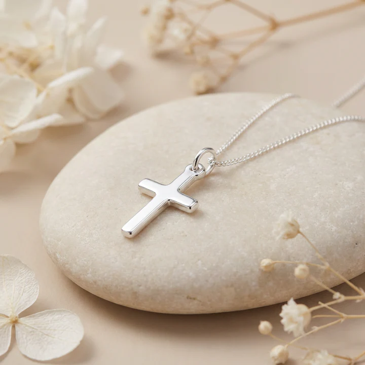 Sterling Silver small plain cross pendant, shown on sea stone with dried botanicals