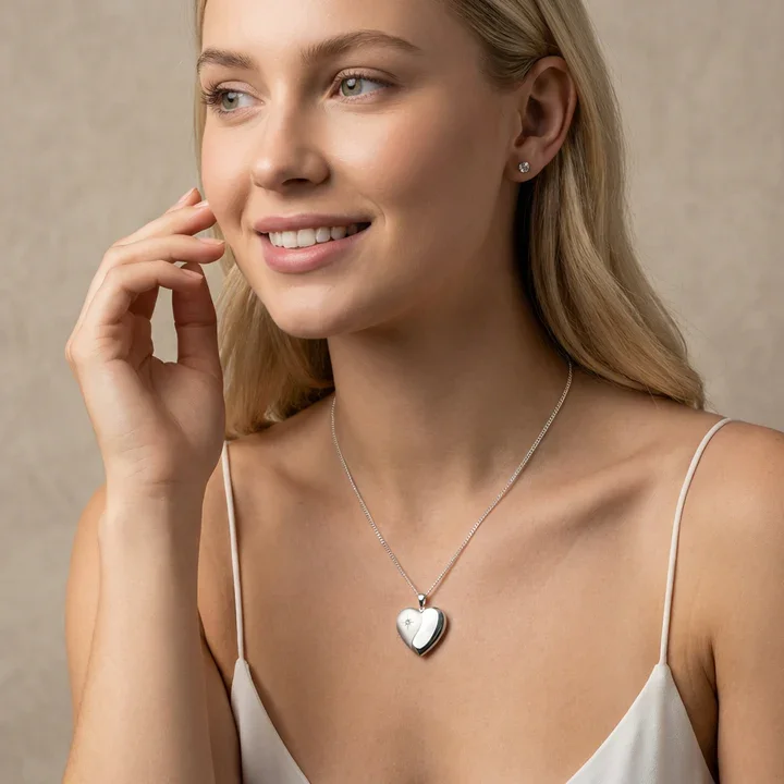 Sterling Silver heart locket with diamond. Star-set stone, satin and mirror polish contrast, shown on model at neckline giving scale