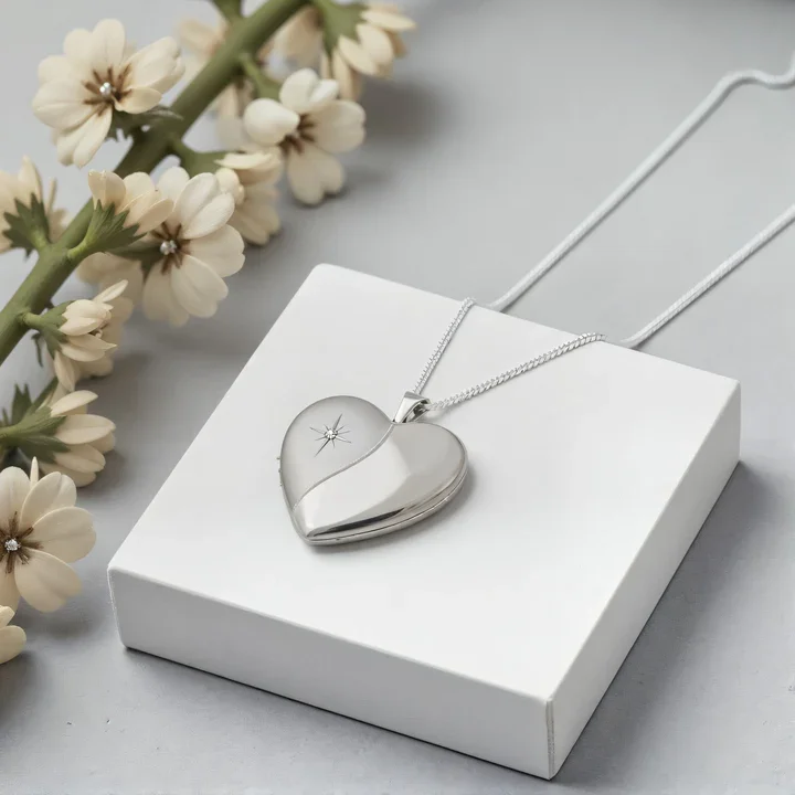 Sterling Silver heart locket with diamond. Star-set stone, satin and mirror polish contrast, shown on display pad with dried botanicals