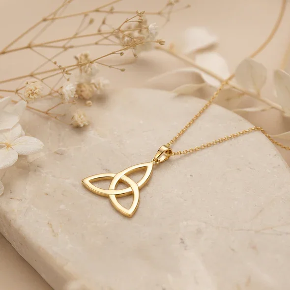 Gold Plated Sterling Silver Celtic Trinity Knot Pendant, triquetra design, mirror polish, shown on sea stone with dried botanicals