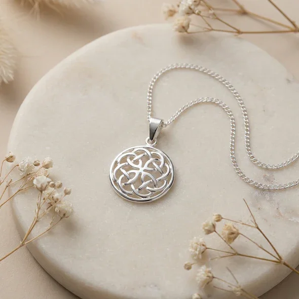 Sterling Silver Celtic Knotwork Round Pendant, open five-loop interlaced design, high mirror polish, shown on sea stone with dried botanticals