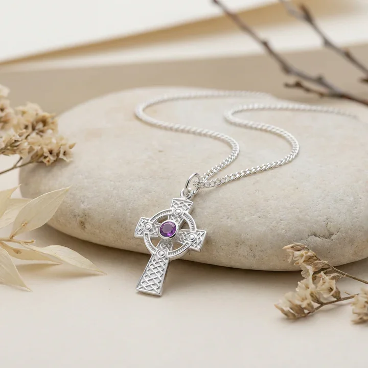 Sterling Silver Celtic cross pendant with amethyst, shown on sea stone with dried botanicals