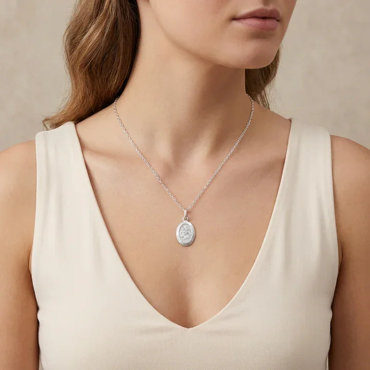 Sterling Silver oval St Christopher pendant. Embossed figural scene, shown on model at neckline giving scale