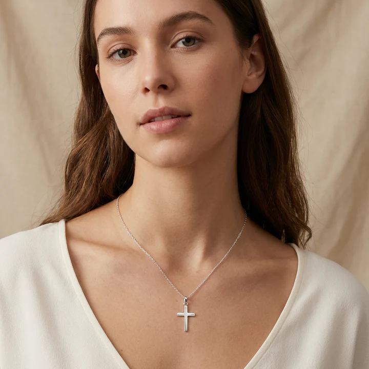 Lightweight Sterling Silver plain polished Latin cross pendant, worn on model at neckline showing pendant drop and scale