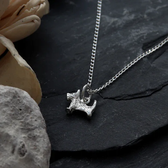 Sterling Silver Scottish Terrier Pendant, sculpted Scottie dog form, engraved coat detail, shown on Scottish slate with sea stone and dried botanicals