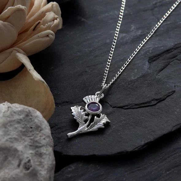 Sterling Silver Scottish Thistle Pendant, round amethyst bezel set, naturalistic leaf detail, shown on Scottish slate with dried botanicals