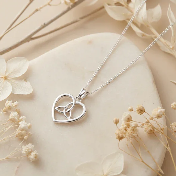 Sterling Silver Celtic Heart Trinity Knot Pendant, open heart frame, triquetra detail, shown on sea stone with dried botanicals