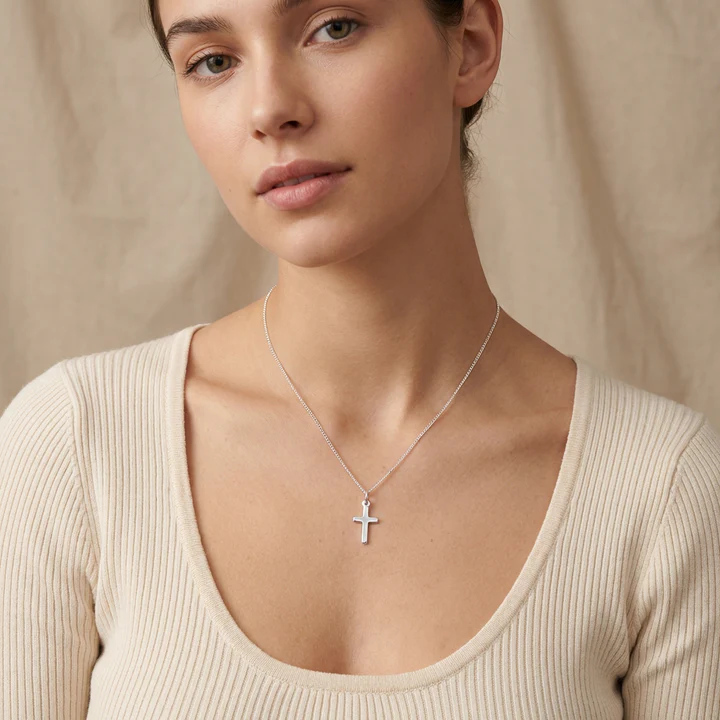 Sterling Silver small plain cross pendant, shown on model at neckline giving scale