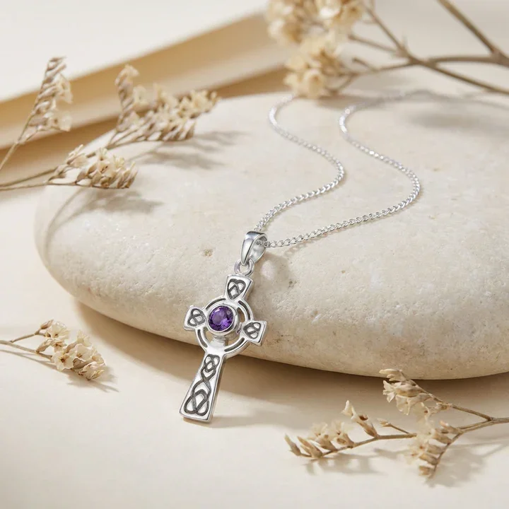 Sterling Silver Celtic cross pendant with amethyst, shown on sea stone with dried botanicals