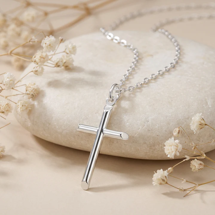 Sterling Silver plain cross pendant, round tubular arms, shown on sea stone with dried botanicals